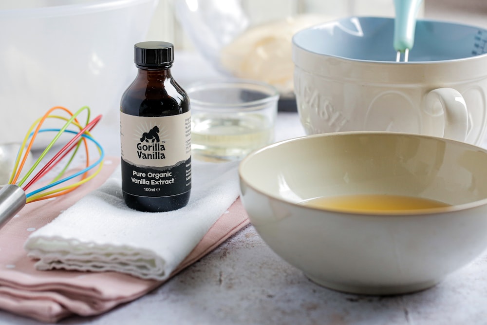 white ceramic bowl beside black glass bottle