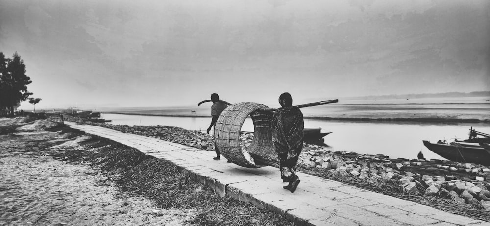 man in black jacket and pants standing on concrete pavement near body of water during daytime