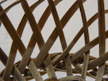 Close-up of hands weaving thin wooden strips into a basket.