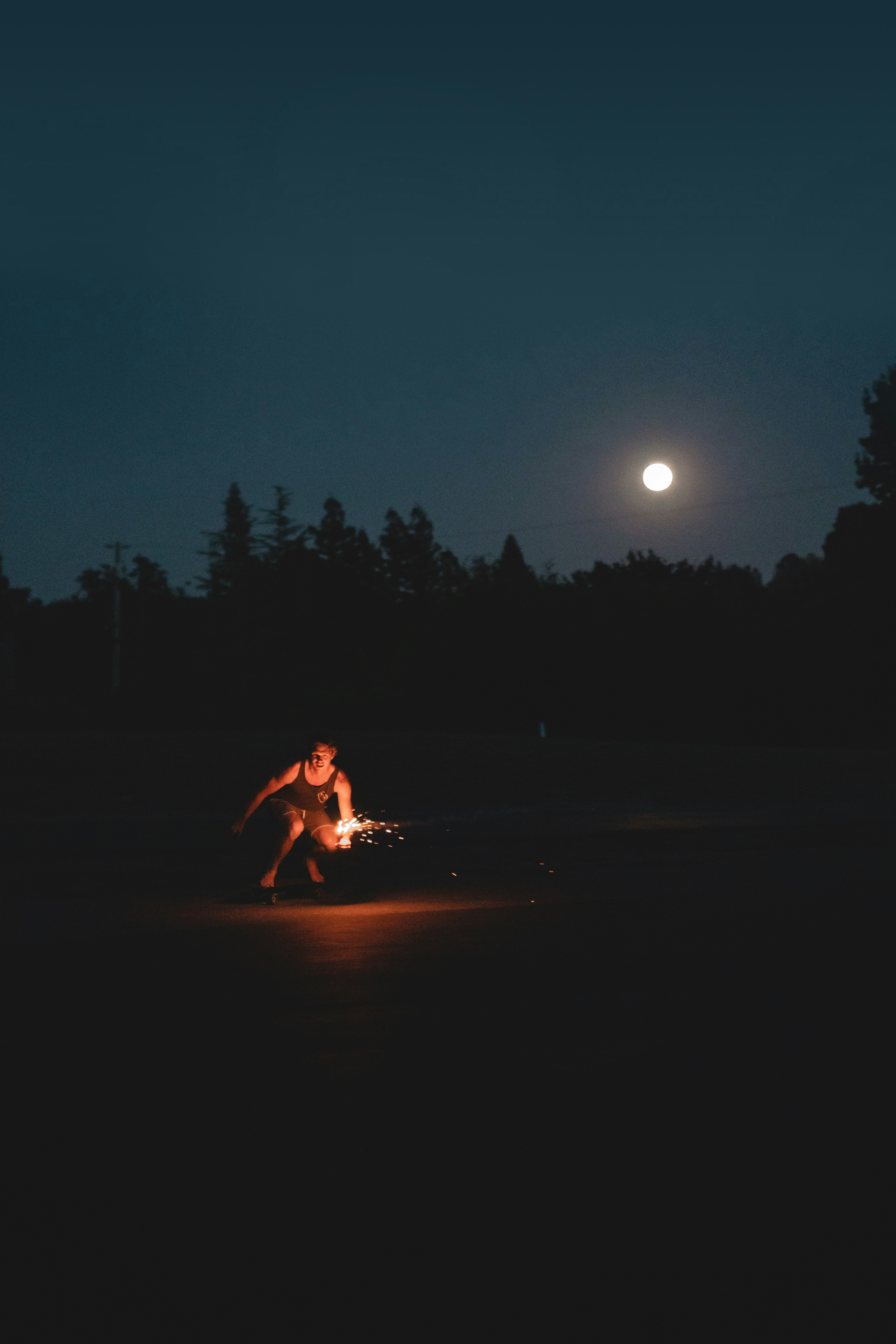 a man kneeling down next to a fire in the dark