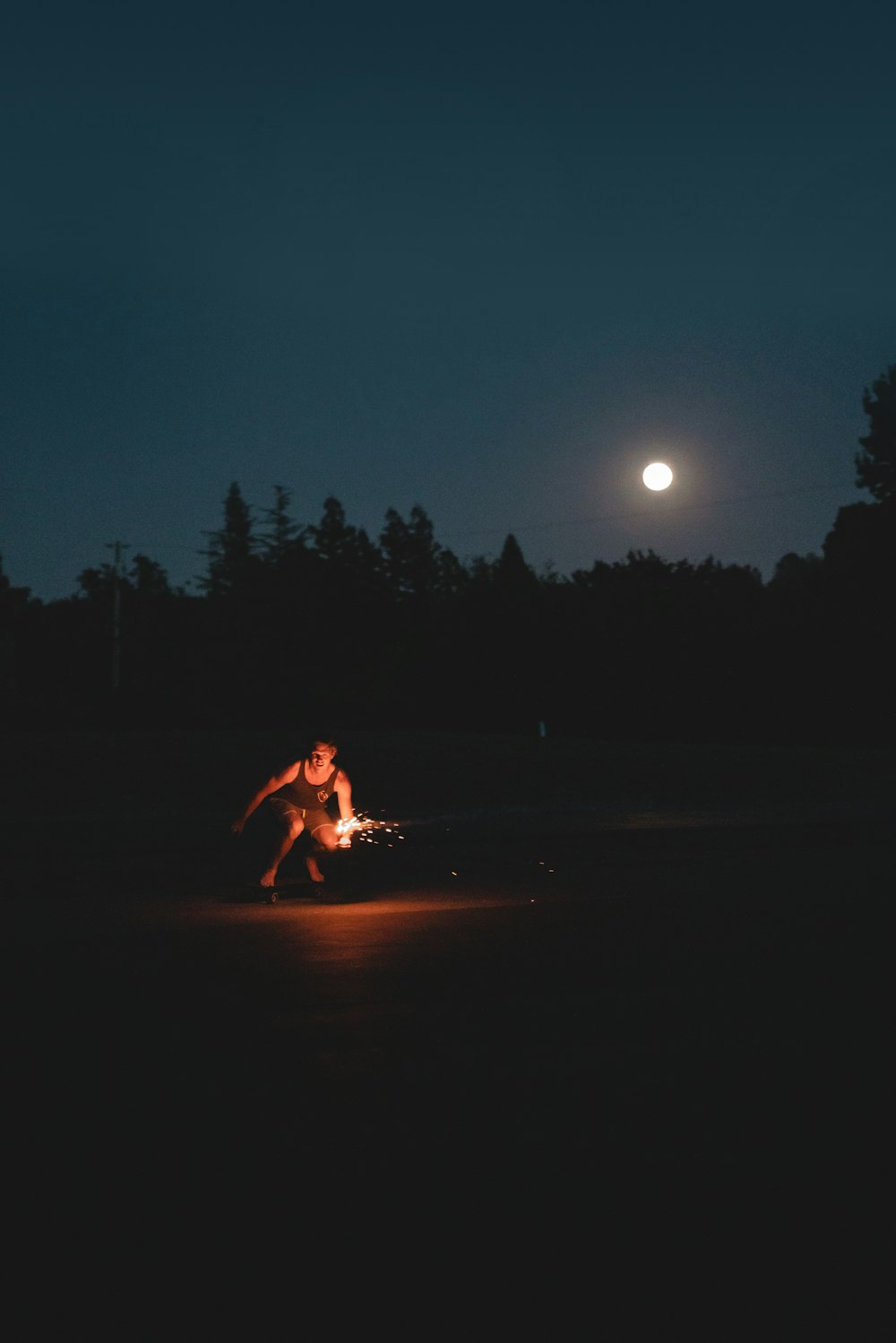 a man kneeling down next to a fire in the dark