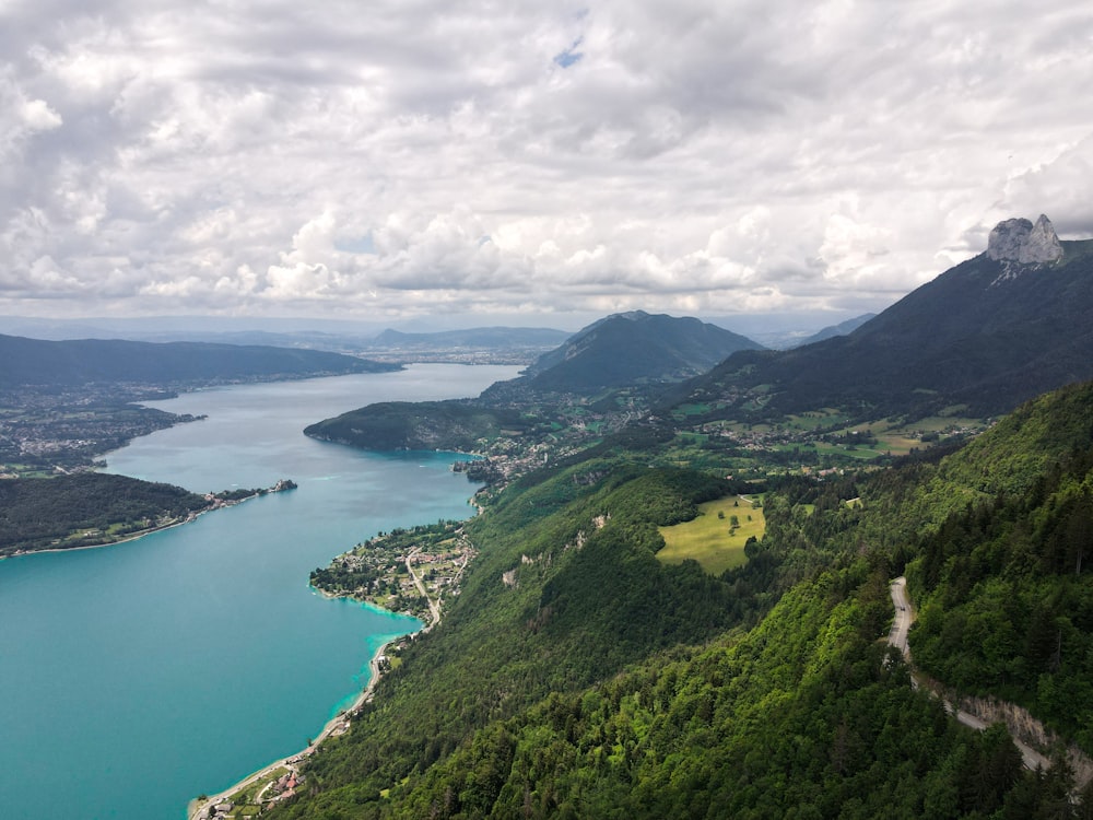 Montaña cubierta de hierba verde junto al cuerpo de agua bajo nubes blancas durante el día