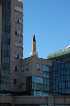 A modern madrasah building with students engaging in outdoor learning activities under a clear sky.