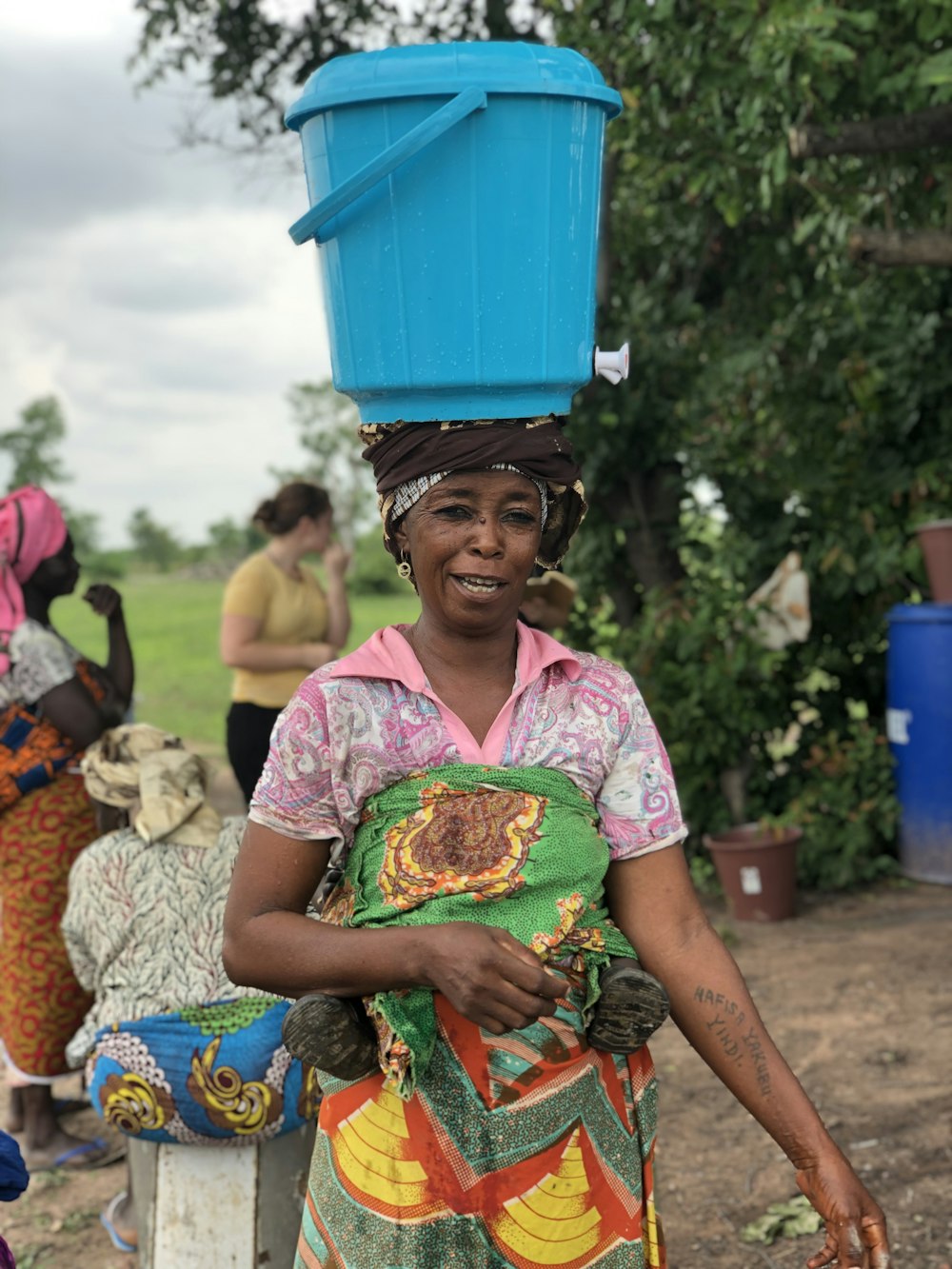 woman in pink and white floral shirt holding blue plastic container