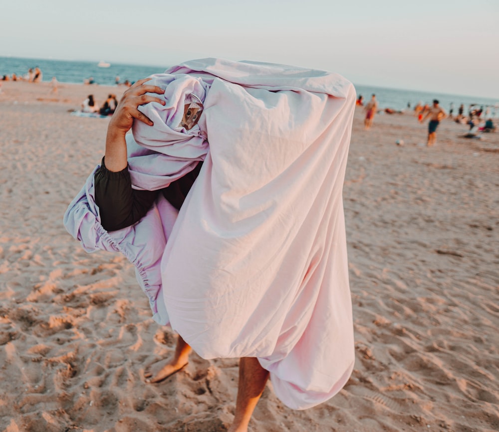 woman in white dress walking on beach during daytime