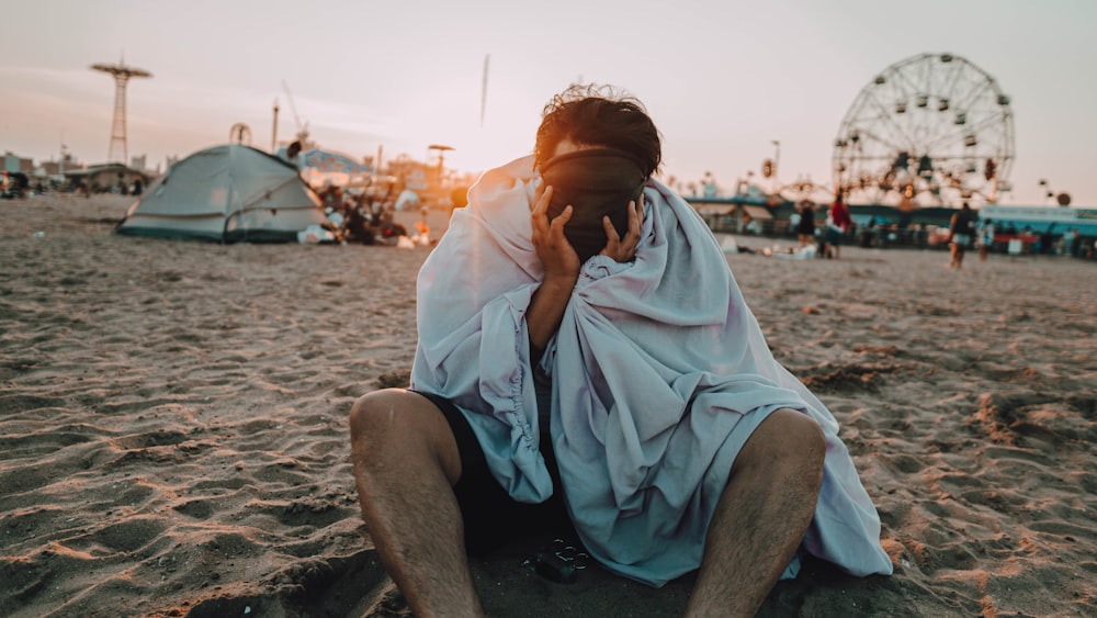 man in blue button up shirt sitting on beach during daytime