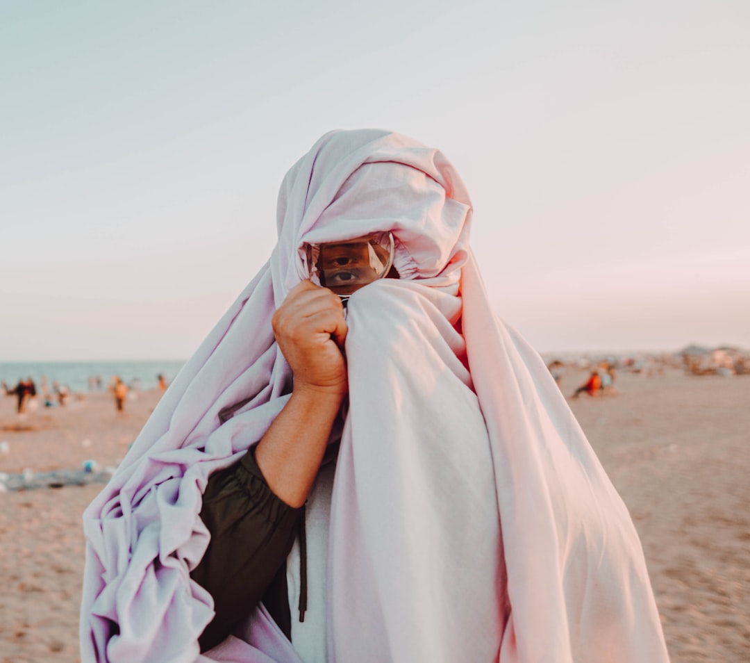 woman in white hijab covering her face with white textile