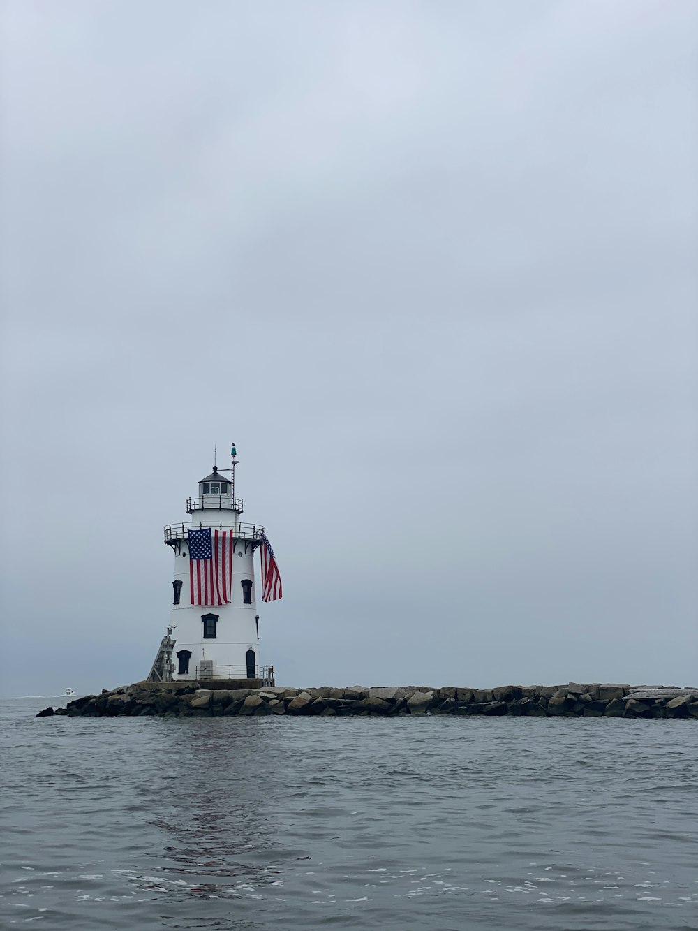 white and red lighthouse on brown rock formation near body of water during daytime