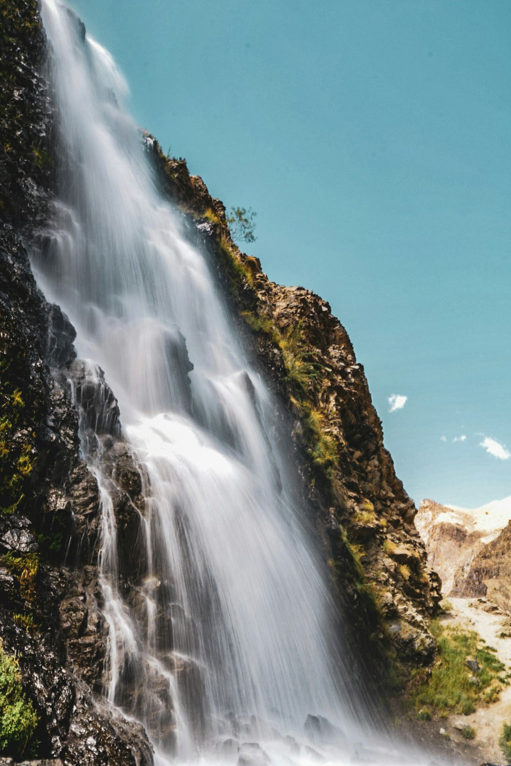 waterfalls on brown rocky mountain under blue sky during daytime