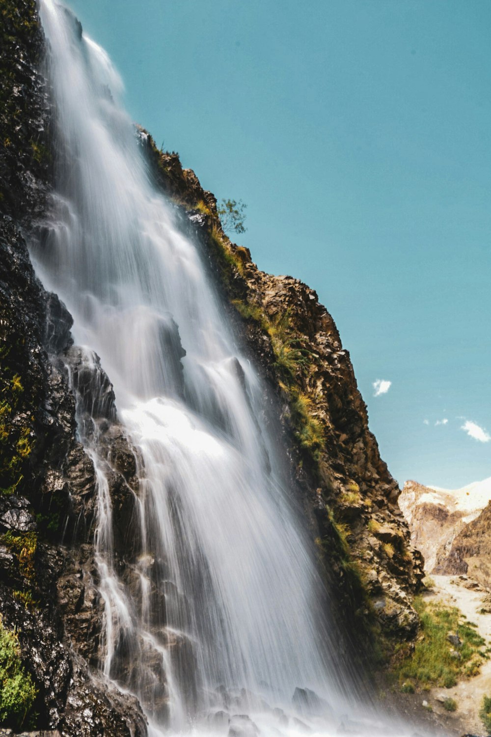 Cascate sulla montagna rocciosa marrone sotto il cielo blu durante il giorno