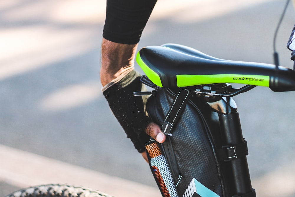 person in black and white nike athletic shoes riding on black and green motorcycle during daytime