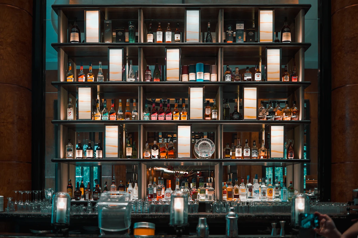 Glass bottles arranged on a wooden bar shelf