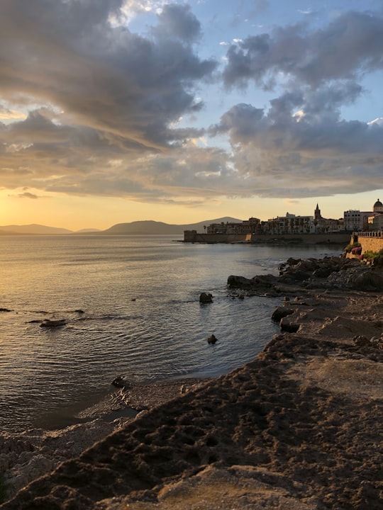 body of water near brown concrete building during daytime in Alghero Italy