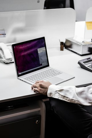 Hands typing on a laptop at an office desk