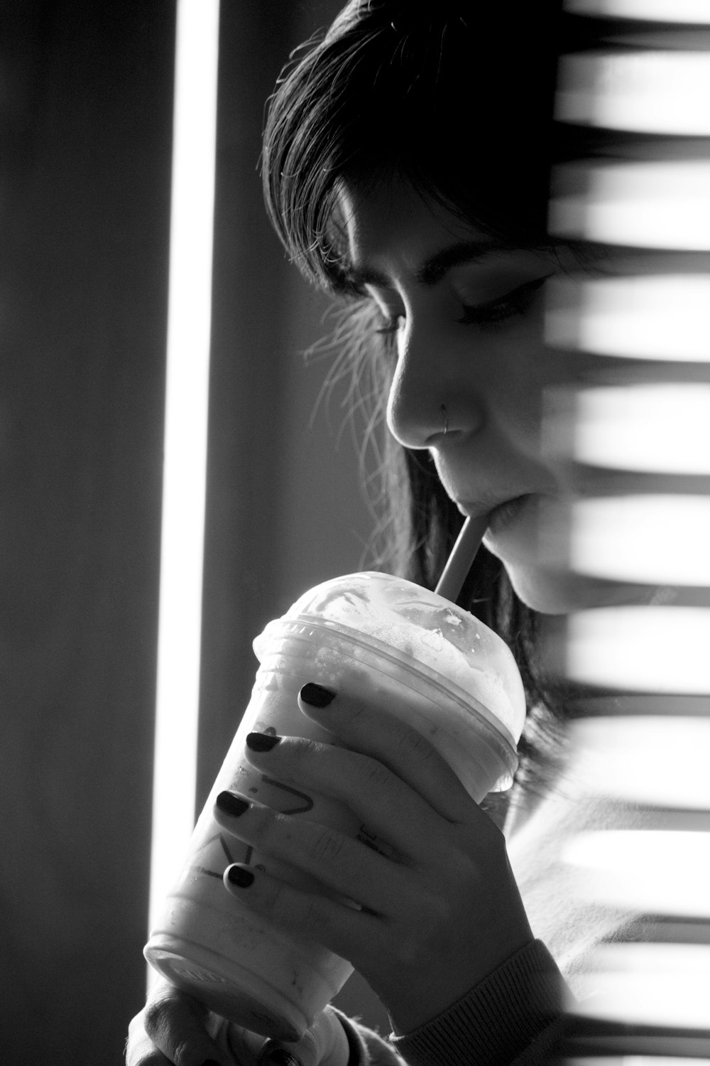 grayscale photo of woman drinking from plastic cup