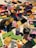 A colorful assortment of various Lego pieces scattered on a surface, including blocks, wheels, and connectors in a variety of shapes and sizes.