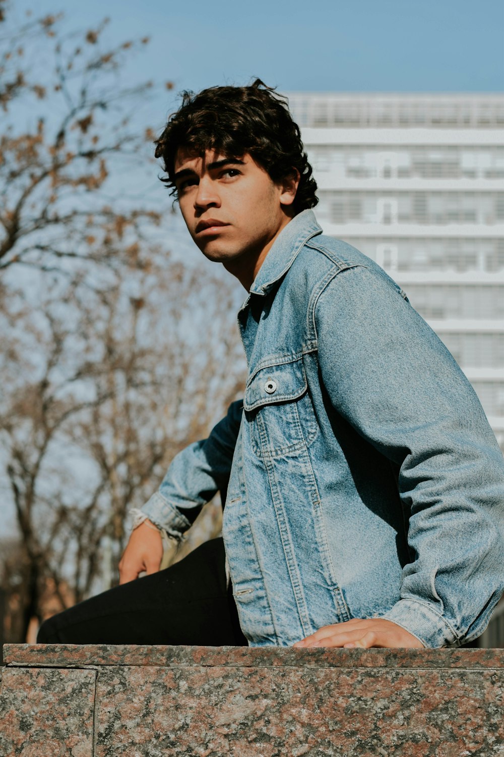 man in blue denim jacket sitting on black chair