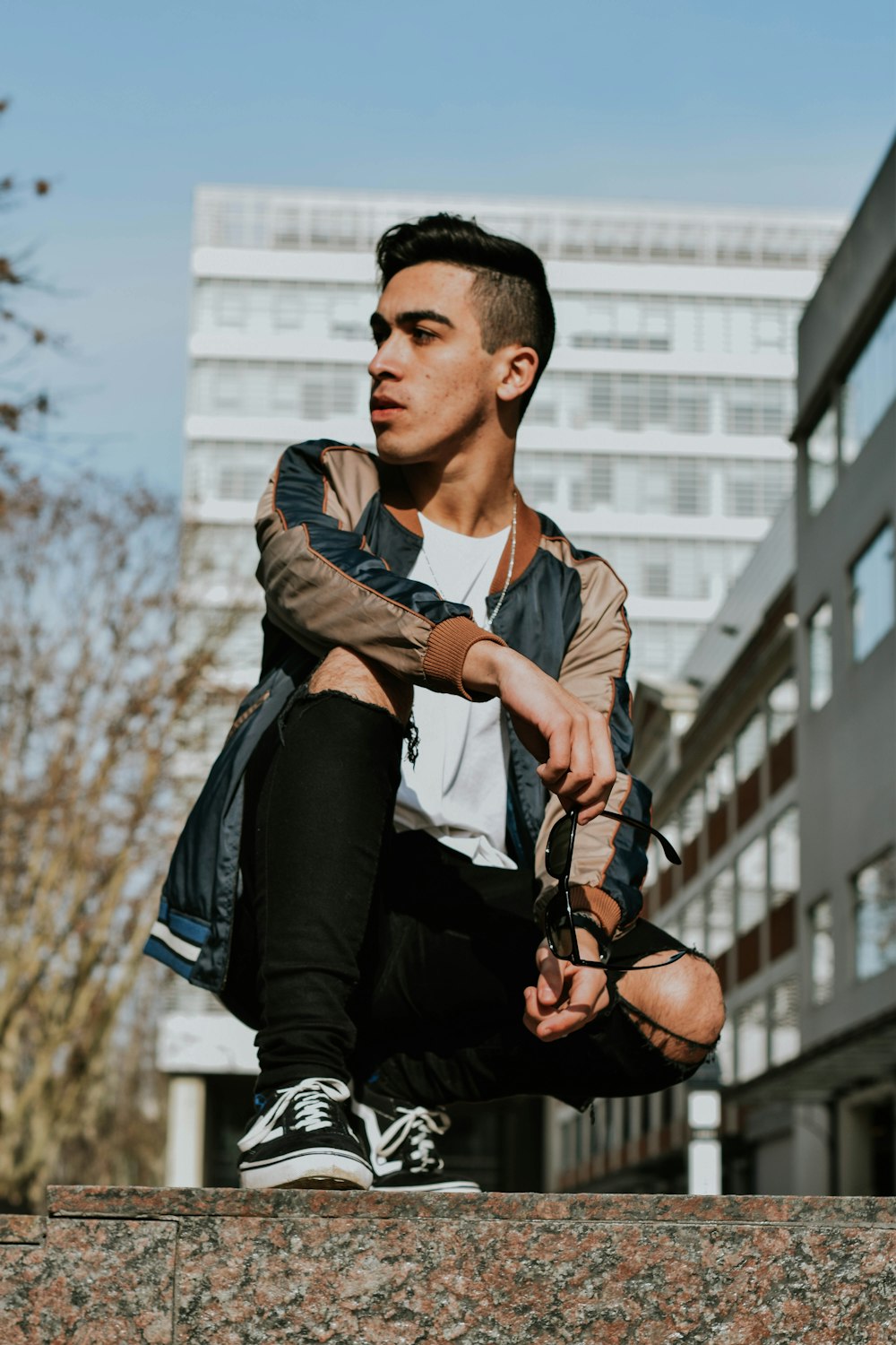 man in black and white striped dress shirt and black pants sitting on brown rock during