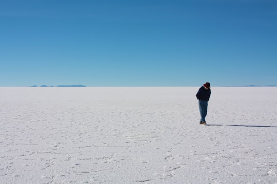 man in black jacket walking on white sand during daytime in Uyuni Bolivia
