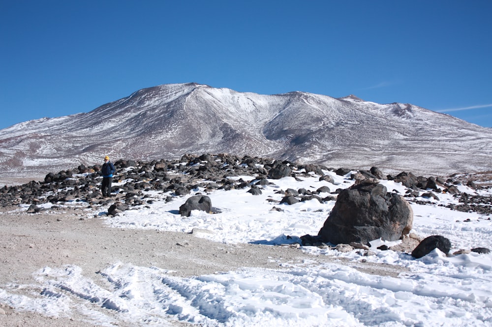 Personnes sur un champ enneigé près de la montagne sous un ciel bleu pendant la journée