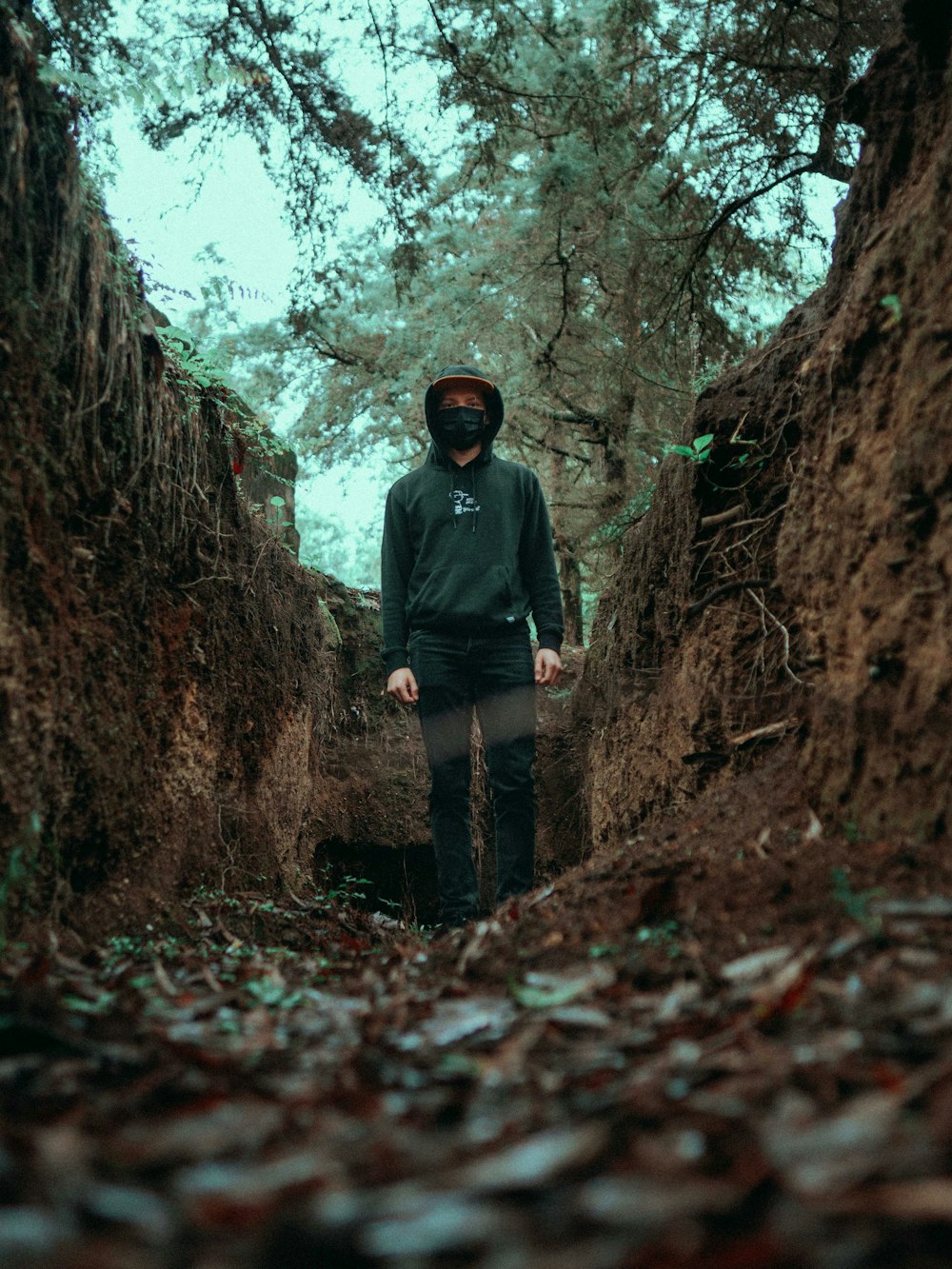 man in black jacket and black pants standing in the middle of the woods during daytime