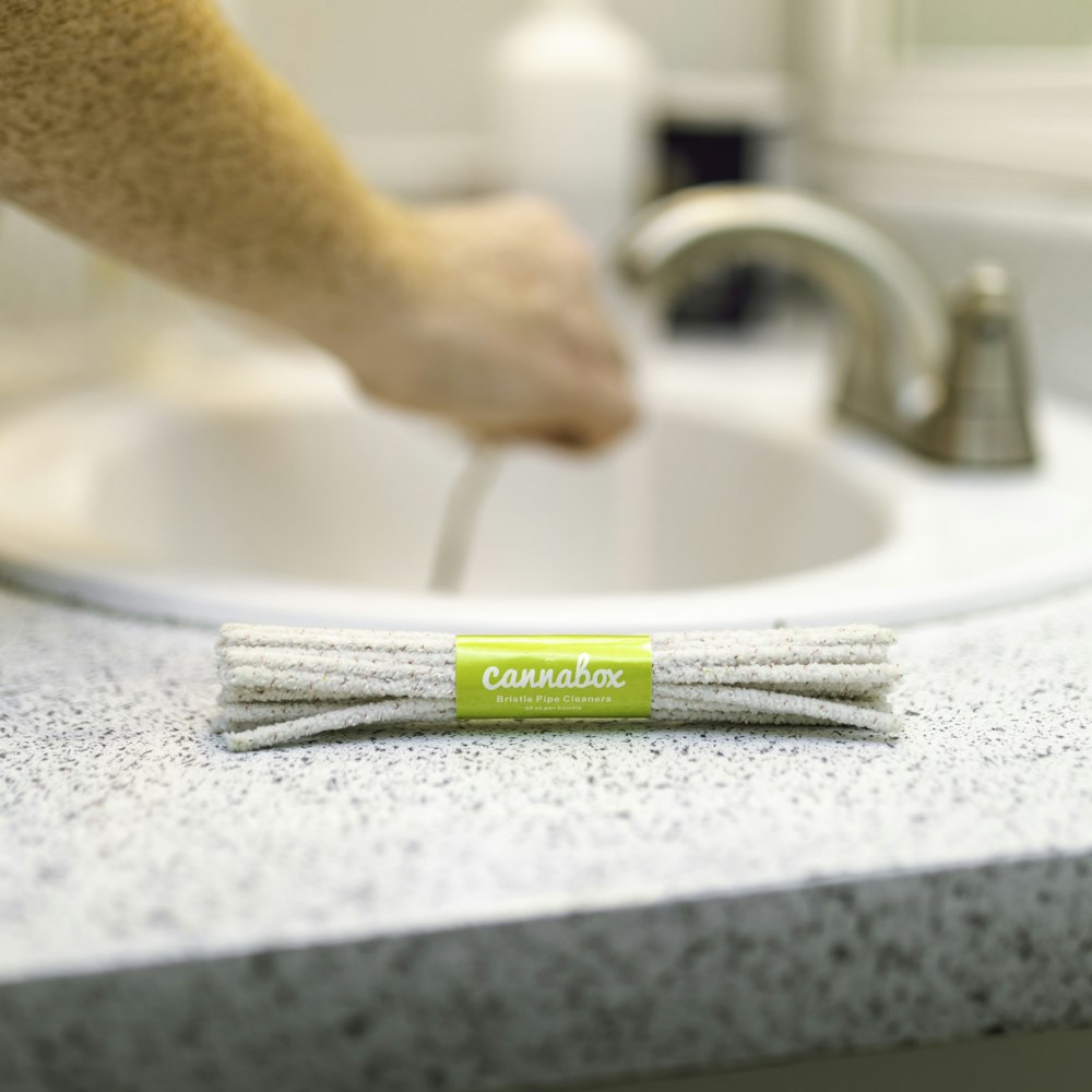 person holding white and green toothbrush