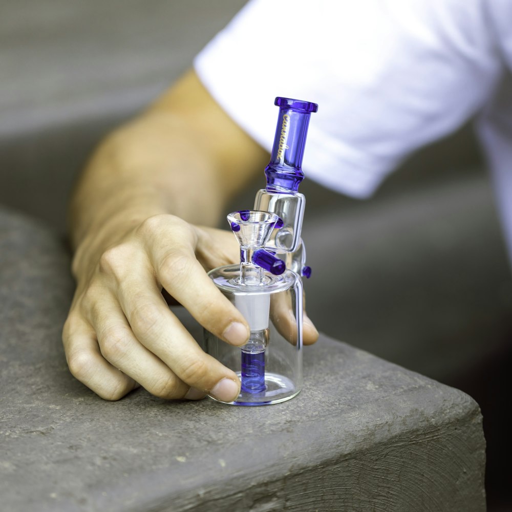 person in white long sleeve shirt holding blue and silver e cigarette