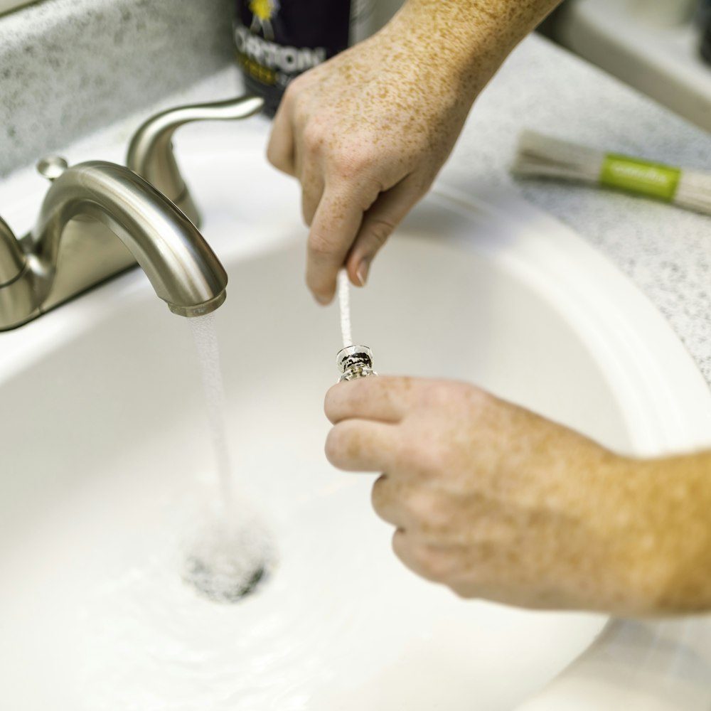 person holding silver steel faucet