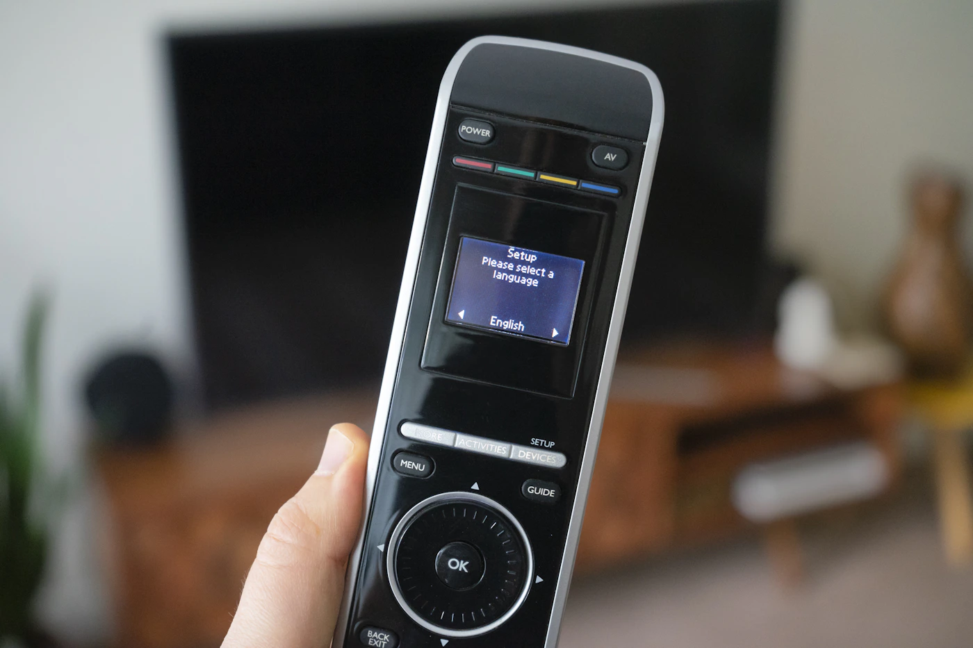 Pessoa usando controle remoto para navegar canais de IPTV à noite