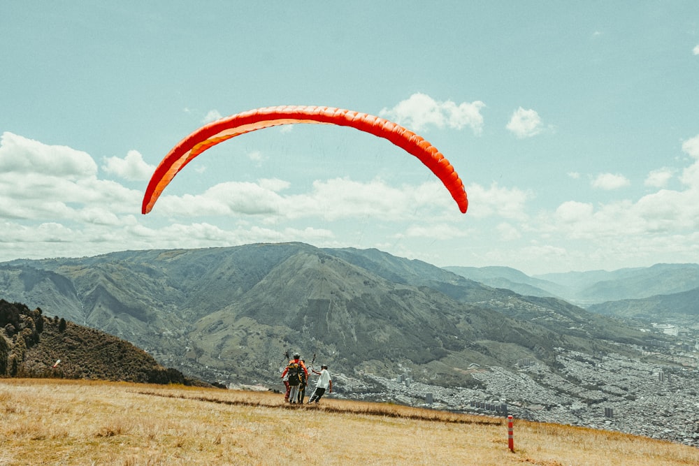 a person on a hill flying a red kite