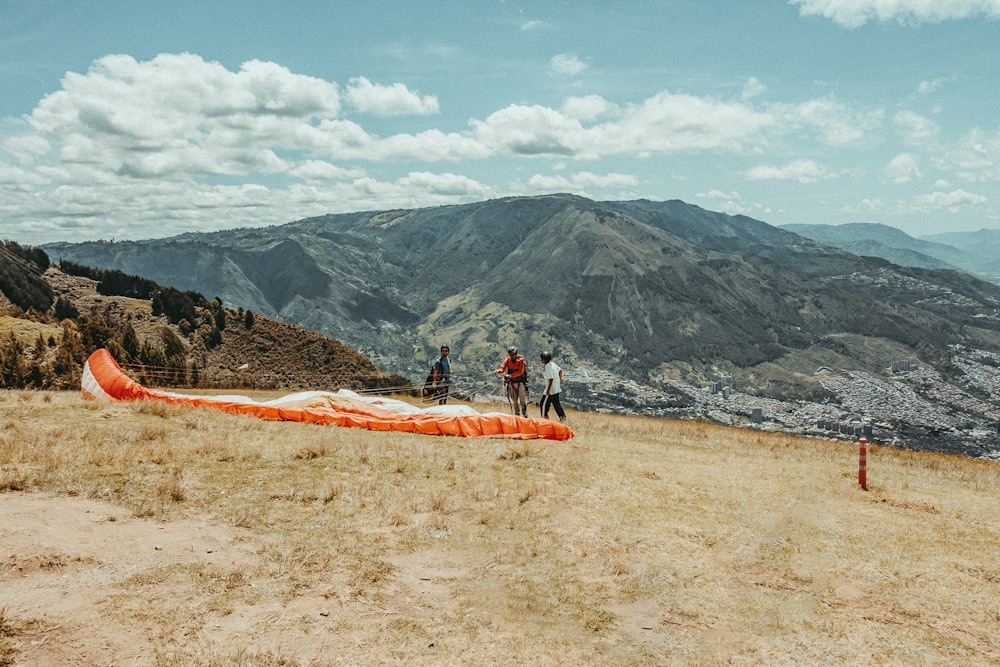 a group of people standing on top of a grass covered hillside