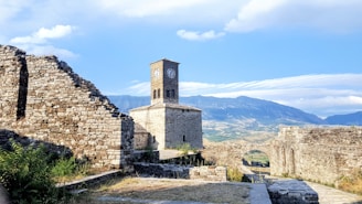 brown brick building near green grass field and mountain under blue sky during daytime