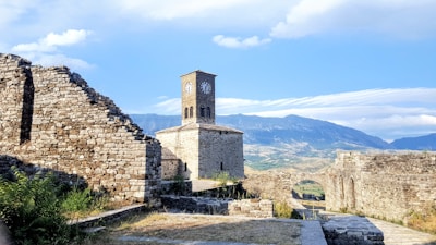 brown brick building near green grass field and mountain under blue sky during daytime