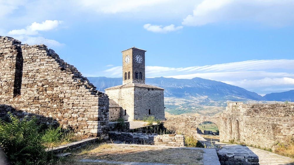 brown brick building near green grass field and mountain under blue sky during daytime