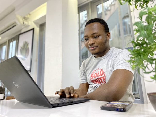 man in crew neck t-shirt using laptop computer and messaging his coach on the Dollar Harmony app