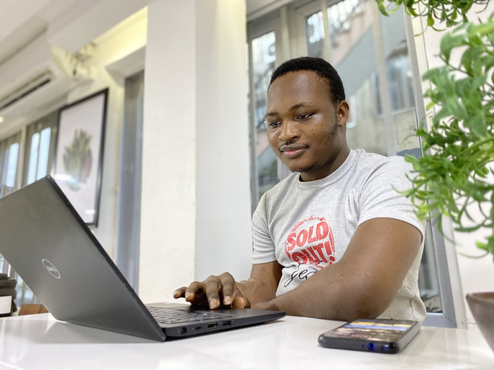 Hombre en camiseta blanca y roja con cuello redondo usando computadora portátil