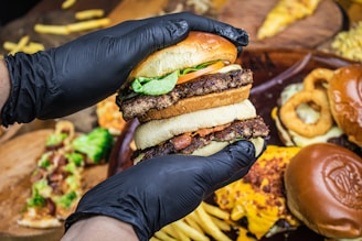 person holding burger with lettuce and cheese