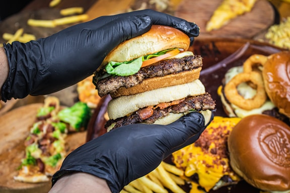 person holding burger with lettuce and cheese
