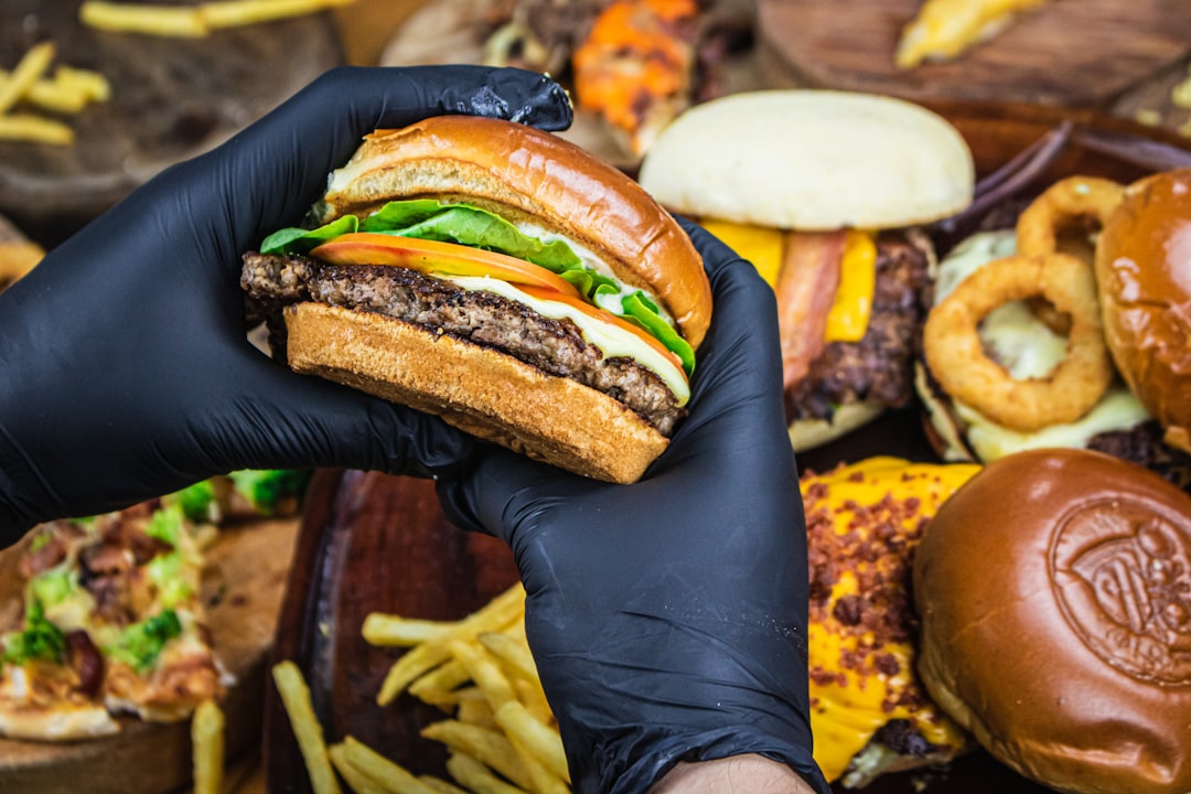 person holding burger with patty and cheese