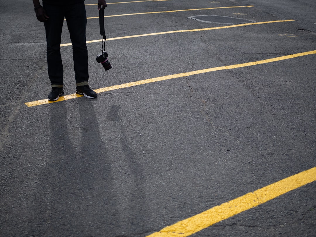 person in black pants walking on gray asphalt road