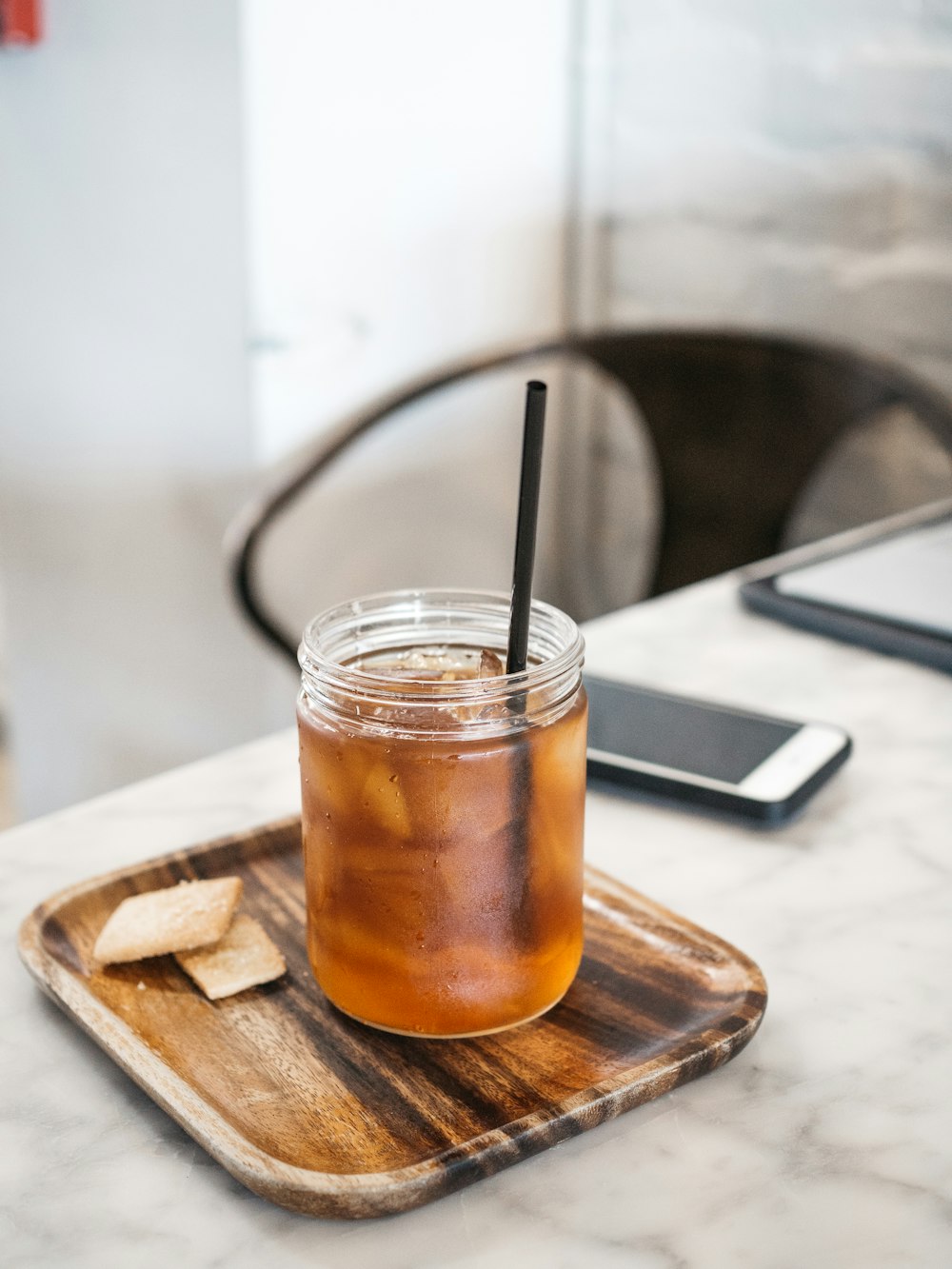 clear drinking glass with brown liquid on brown wooden coaster