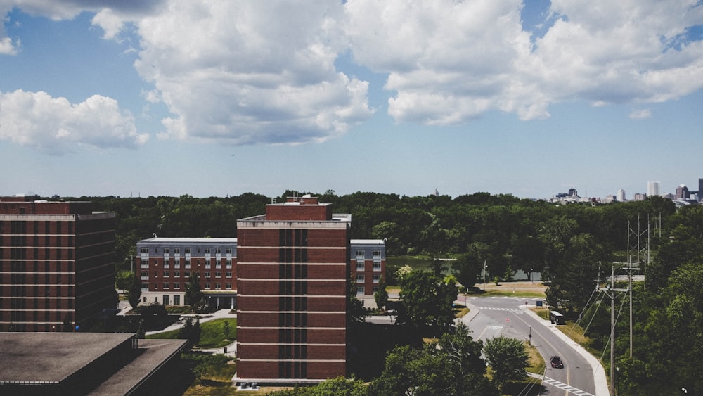 brown and white concrete building near green trees under white clouds and blue sky during daytime