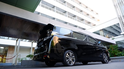 A sleek car parked outside an airport terminal with a driver waiting patiently.