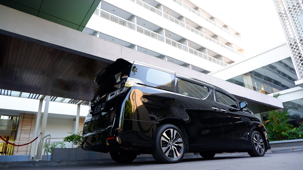 A sleek car parked in front of a modern hotel.