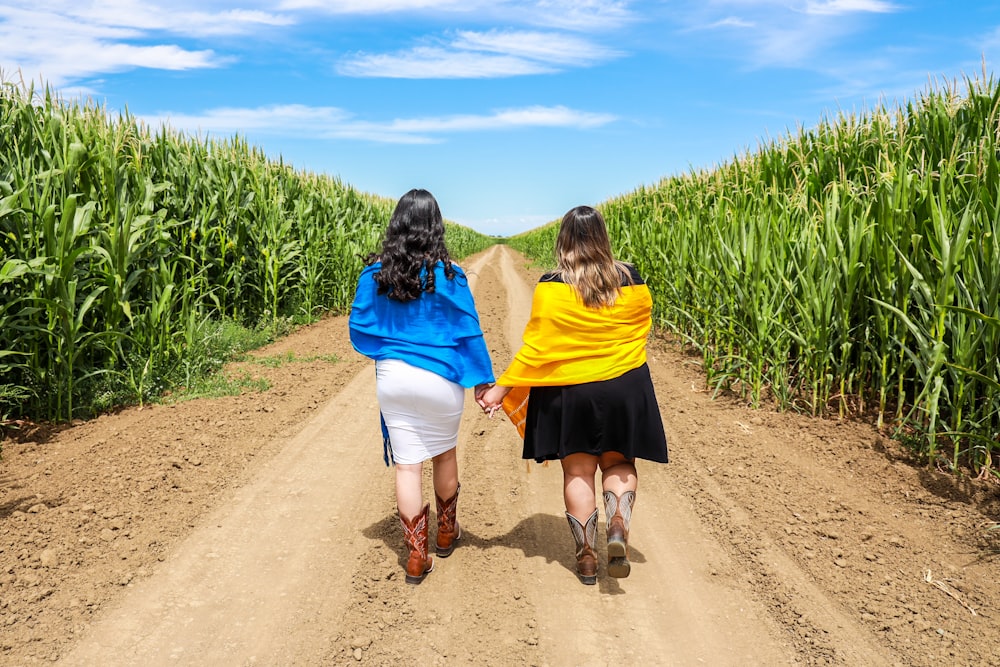 woman in blue jacket and yellow skirt walking on brown sand during daytime