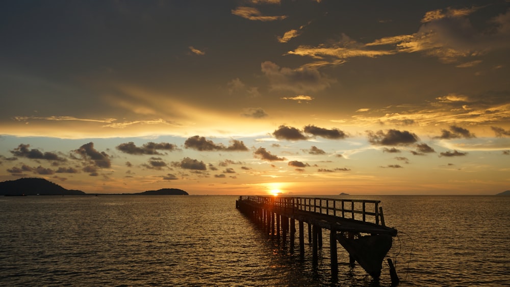 Silueta del muelle de madera en el mar durante la puesta del sol