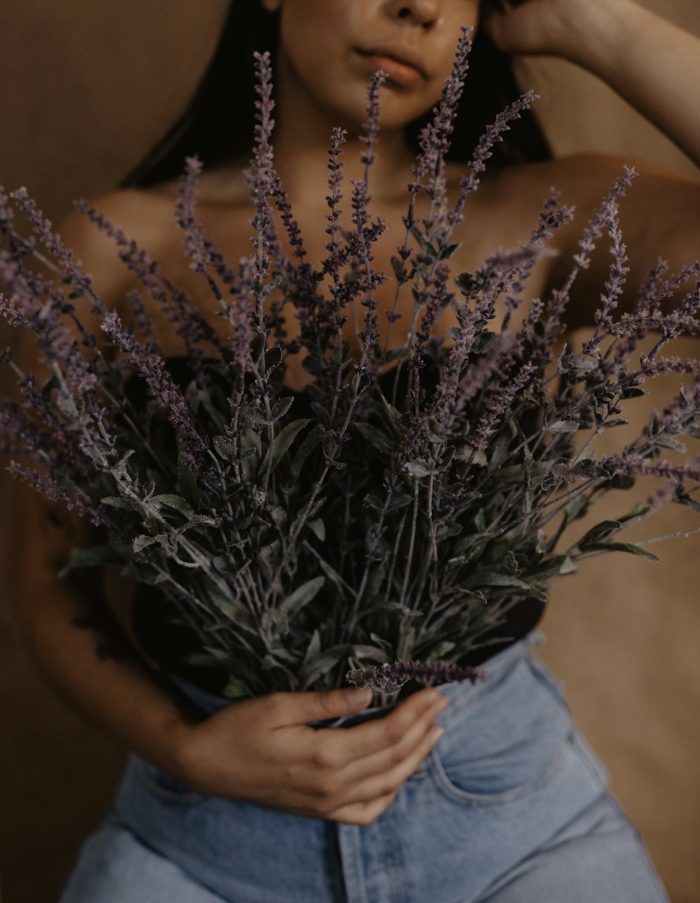 woman in white tube top holding purple flower bouquet