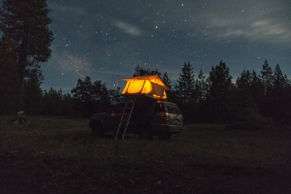 black car parked beside tent under starry night