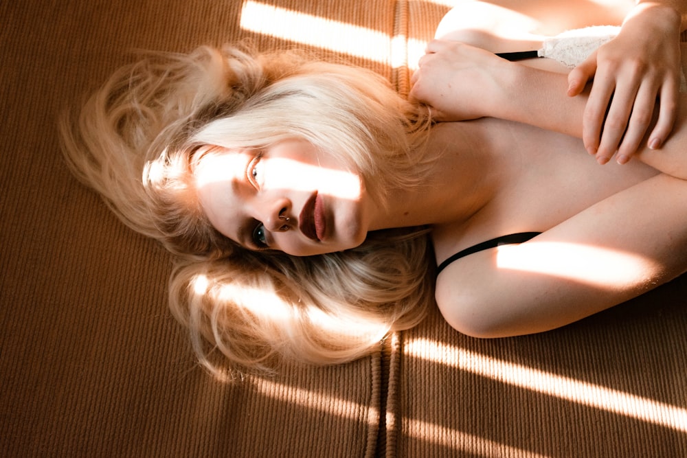 woman in black tank top lying on brown textile