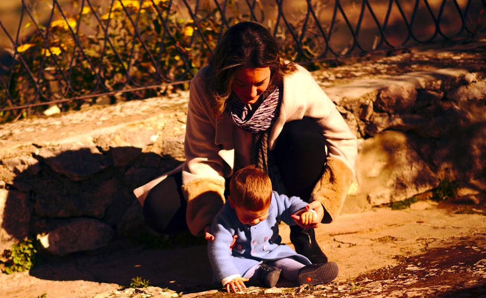 woman in brown jacket carrying baby in white jacket